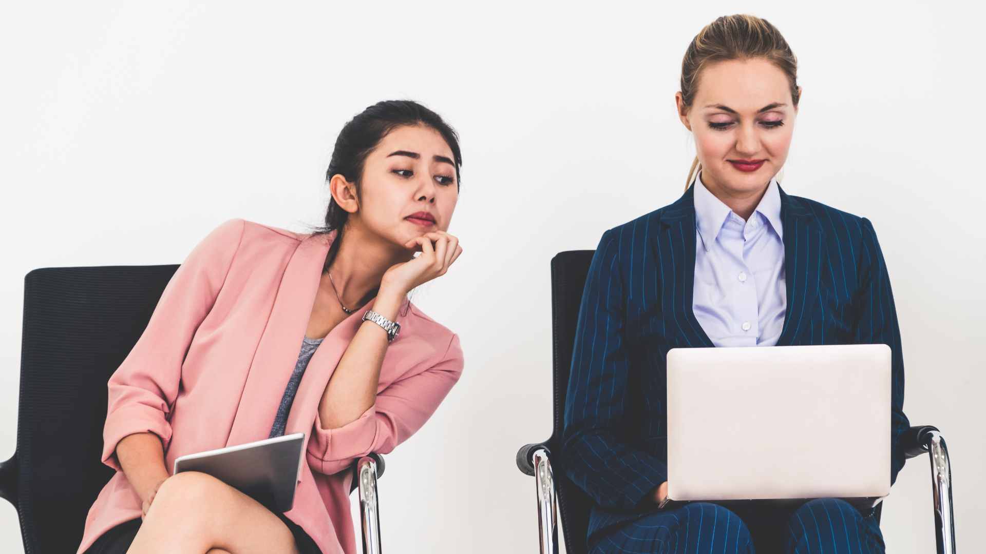 Duas mulheres uma trabalhando no laptop e a outra olhando o que está fazendo, colocando em risco a segurança da informação.